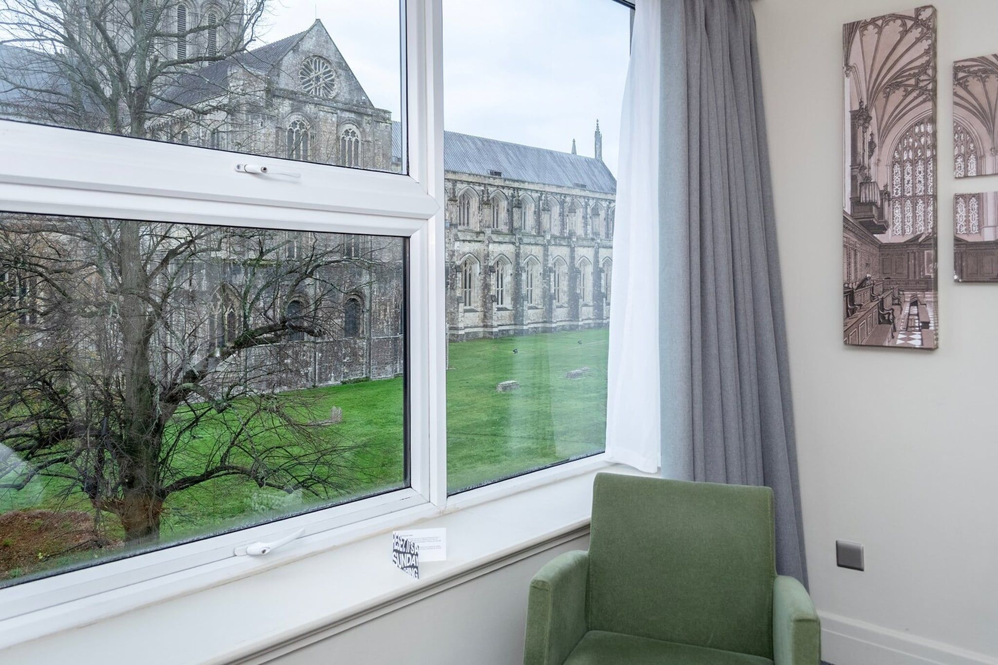 A room with a large window overlooking a historic building and a grassy area.