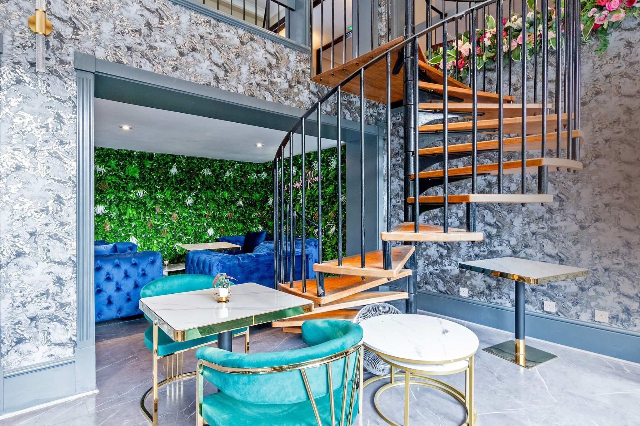 A modern interior with a staircase, seating area, and a green wall.