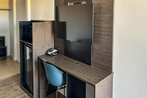 Ein kleiner Arbeitsbereich mit Schreibtisch, Stuhl und einem Flachbildfernseher.