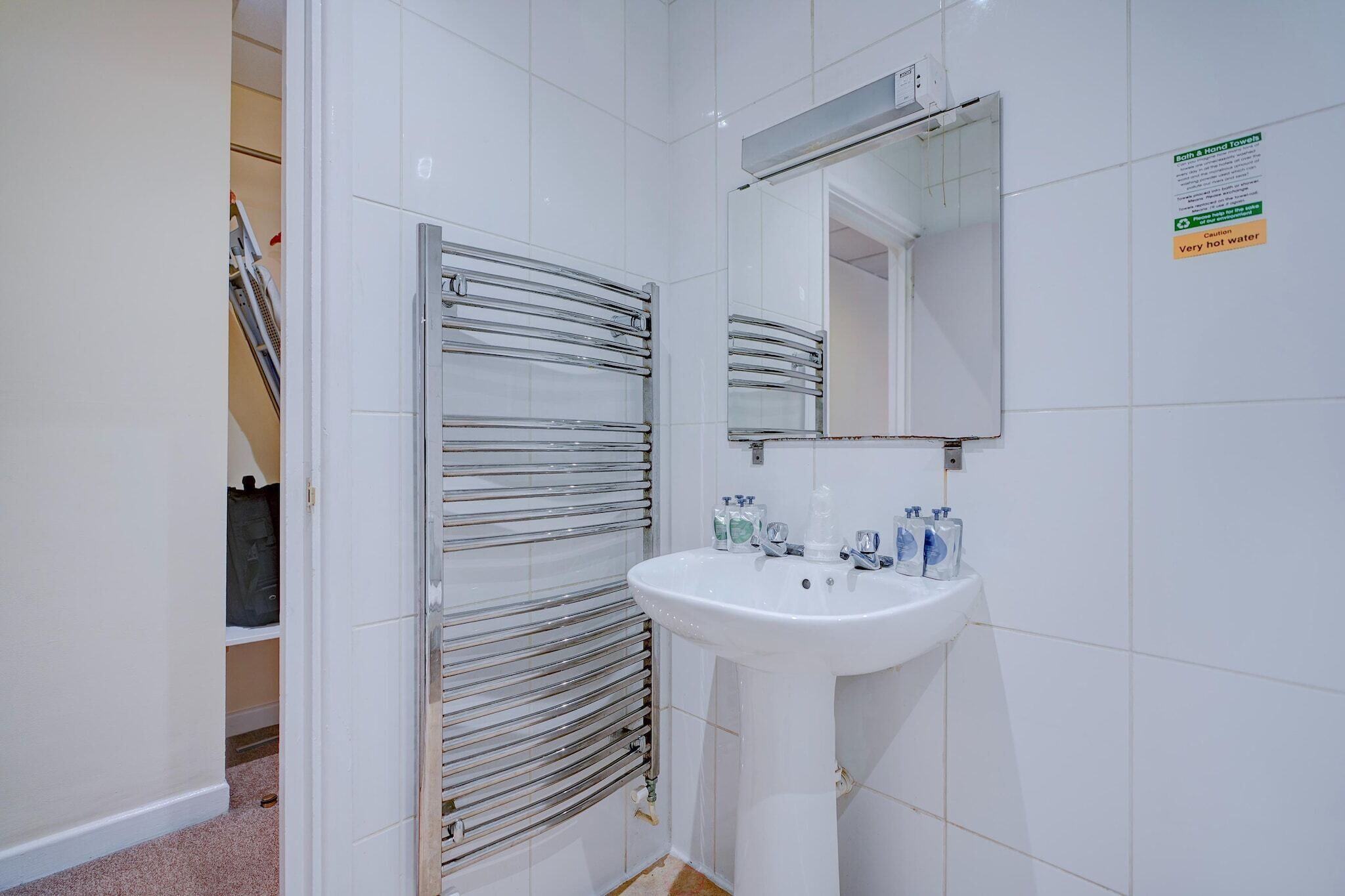 A bathroom with a white sink, mirror, and towel rack.