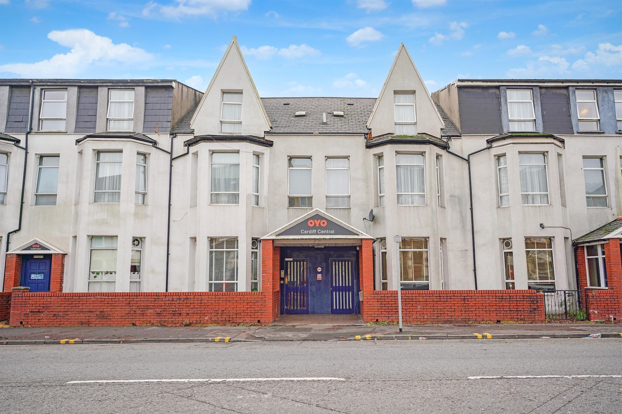 A row of residential buildings with a central entrance marked by a blue door and a sign reading 'OYO Cardiff Central'.