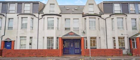 A row of residential buildings with a central entrance marked by a blue door and a sign reading 'OYO Cardiff Central'.
