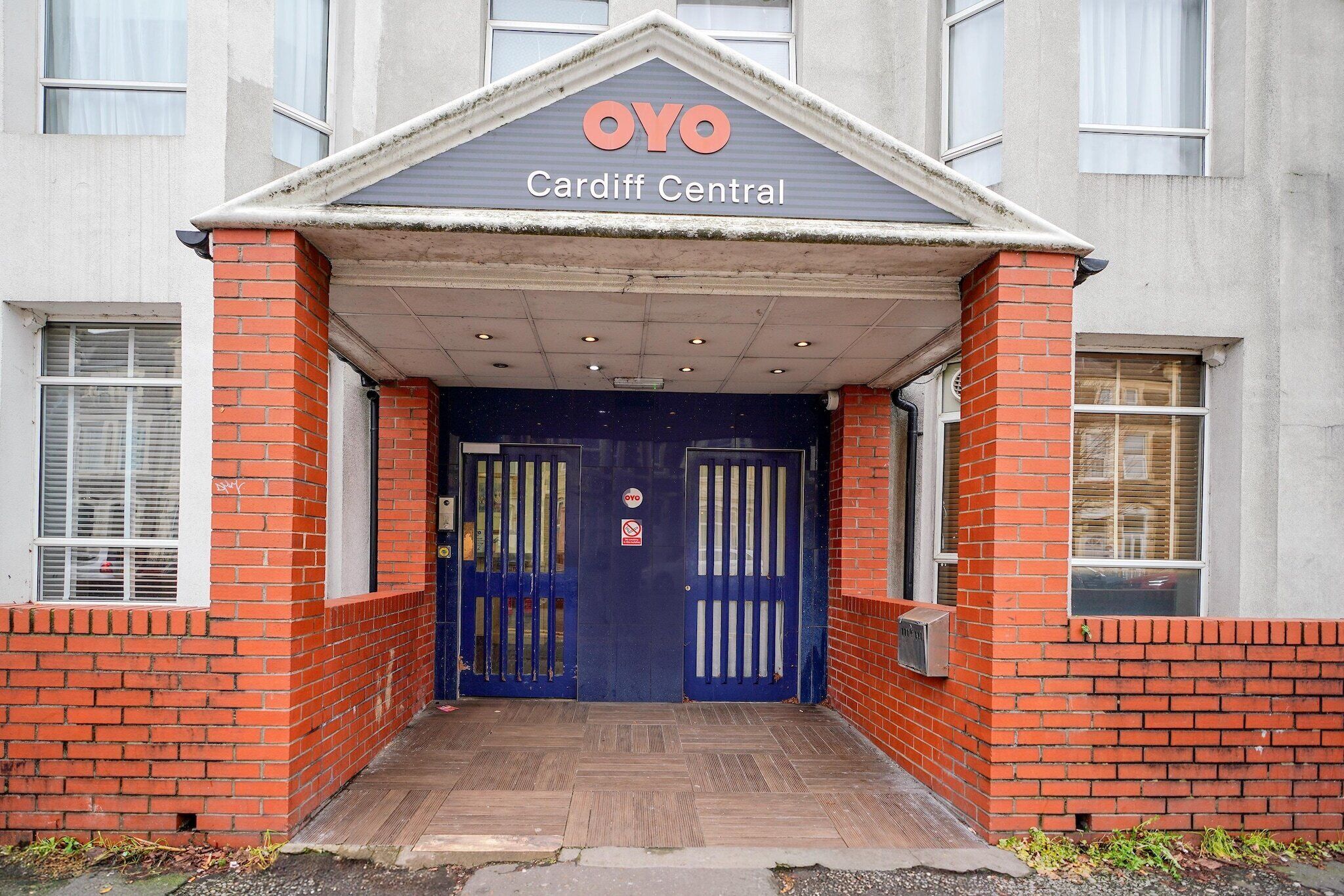 En byggnadsentré med en blå dörr, en skylt med texten ”OYO Cardiff Central” och en fasad av tegel.