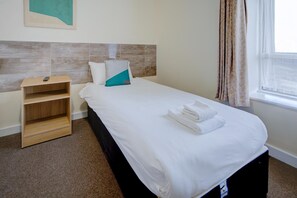 A hotel room with a bed, a wooden nightstand, a wall-mounted painting, and a window with curtains. - OYO Flagship Cardiff Central - Standard Twin Room (Cardiff)