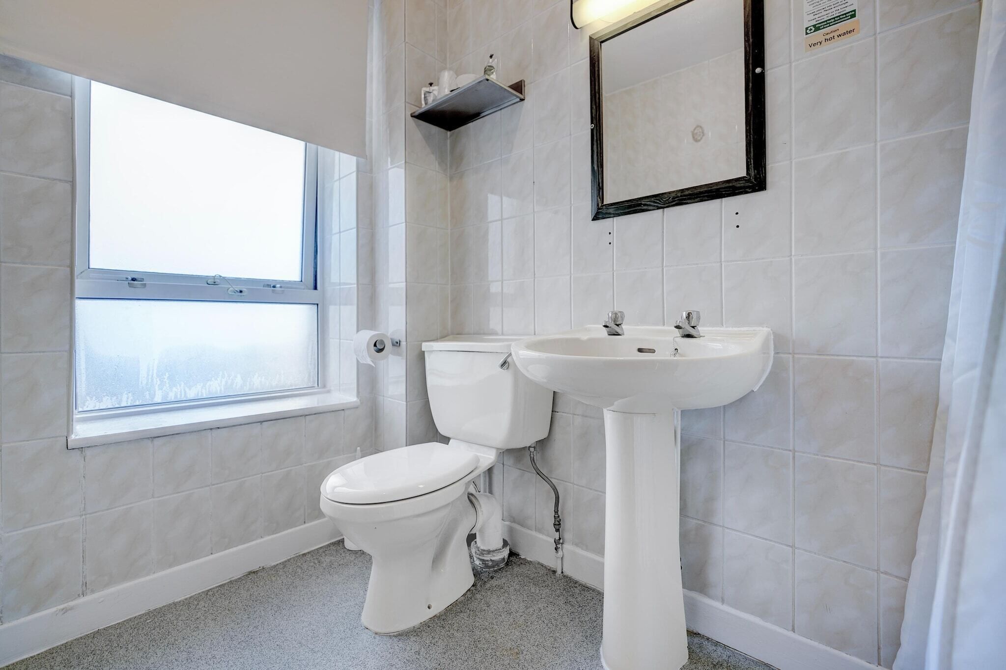 A bathroom with a toilet, sink, and window.