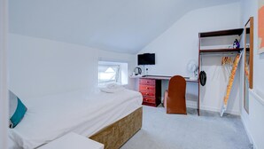 A bedroom with a bed, a desk, a chair, a wardrobe, and a window. - Superior Triple Room (Cardiff)