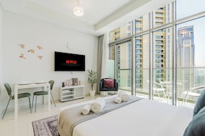 Ein modernes Hotelzimmer mit einem großen Bett, einem Flachbildfernseher, einem Essbereich und einem Balkon mit Blick auf die Stadt.