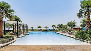 A swimming pool with lounge chairs and palm trees. - PVH - Aykon City - Canal View Studio  (Dubai)