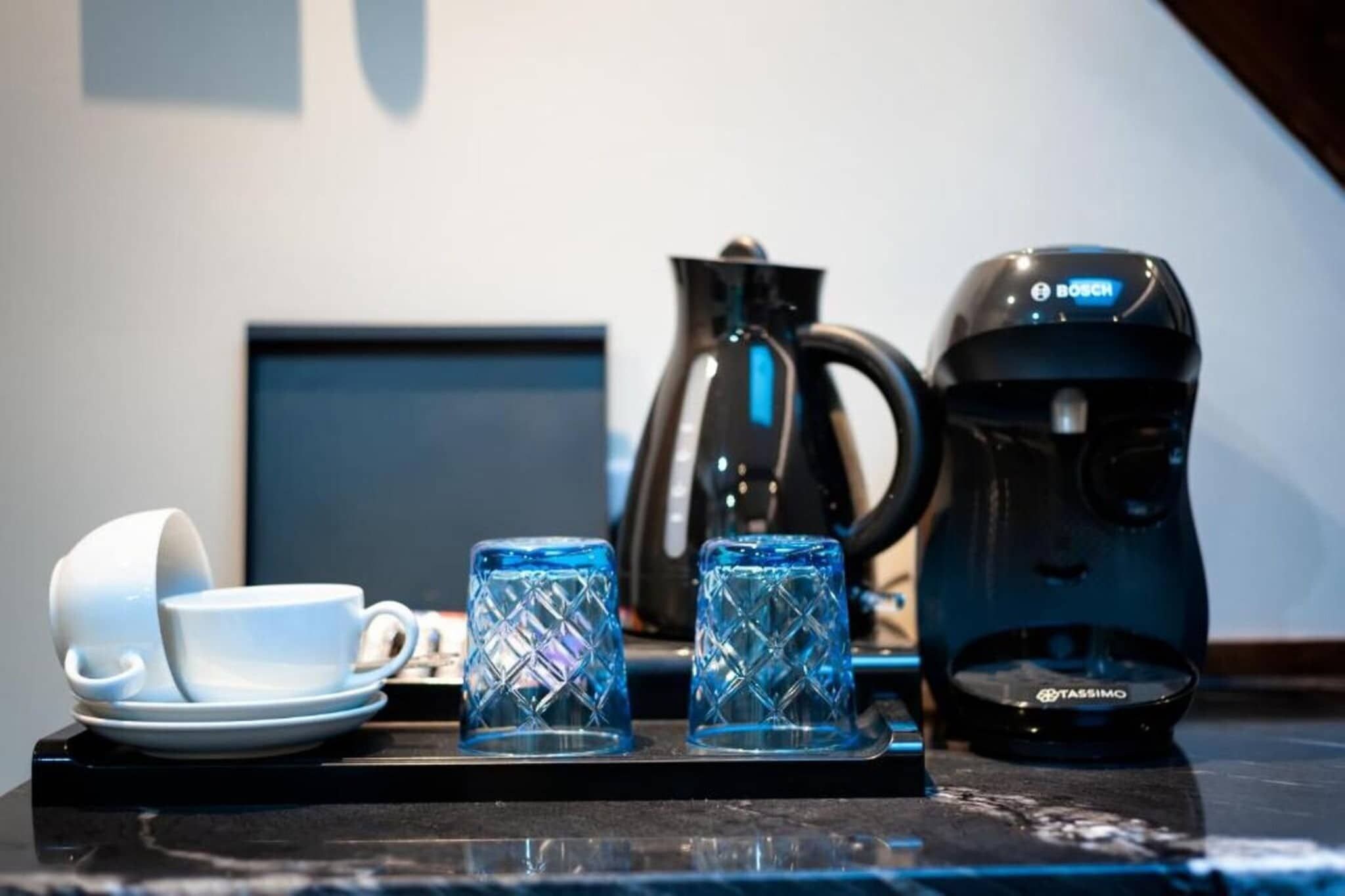 Eine Kaffeemaschine, zwei Tassen und ein Teekessel auf einem Tisch.