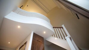 A curved ceiling with a decorative white trim, a wooden door, and a white staircase with a wooden handrail. - Lansbury Studio Suite (London)