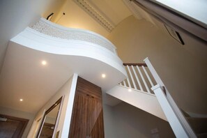 A curved ceiling with a decorative white trim, a wooden door, and a white staircase with a wooden handrail. - Lansbury Studio Suite (London)