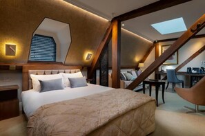 A bedroom with a large bed, a desk, and a chair, with a sloped ceiling and skylight. - Lansbury Studio Suite (London)