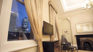 A hotel room with a city view, a fireplace, a television, and a desk with a chair. - Lansbury Studio Suite (London)