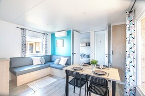 Een moderne woonkamer met een ingebouwde bank, een eettafel met stoelen en een keuken die zichtbaar is door een open deur.