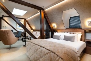 Ein Schlafzimmer mit einem großen Bett, einem Sessel, einem Schreibtisch und einem Oberlicht.
