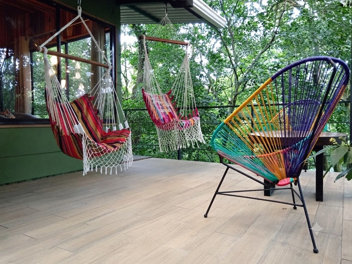 Een houten terras met twee hangmatten en een kleurrijke stoel.
