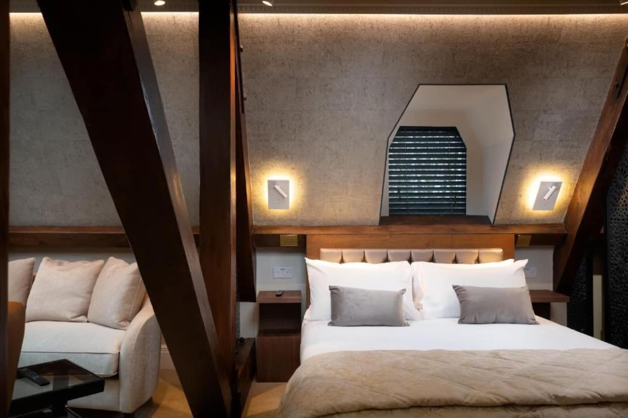 A bedroom with a bed, bedside tables, a chair, and a sloped ceiling with a skylight.