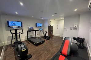 Un gimnasio con cintas de correr, bicicletas estáticas y máquinas de pesas.
