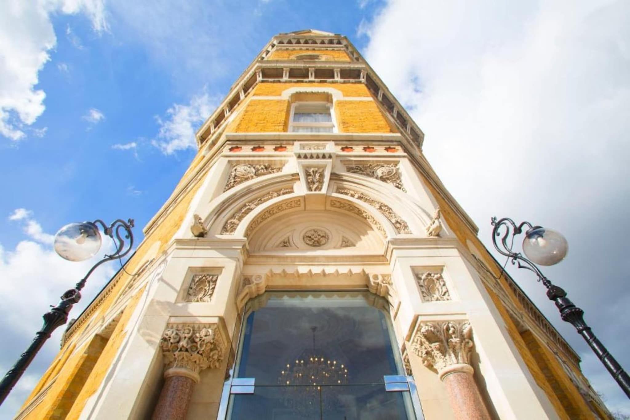 A building with a prominent entrance, ornate architectural details, and two street lamps on either side.