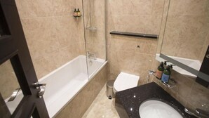 Een badkamer met een bad, toilet, wastafel en douche.