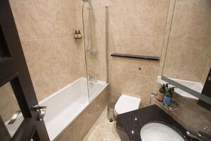Un bany amb banyera, vàter, rentapel i plat de dutxa.