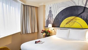 A hotel room with a large bed, a bedside table with a lamp, a vase of flowers, and a window with curtains. - Atlantic Tower Hotel By Sunday - Classic Double room (Liverpool)