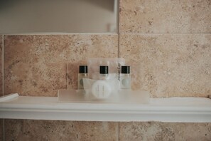 A bathroom shelf with three toiletry bottles and a shower cap.