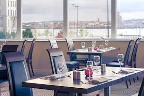A restaurant with tables set for dining, chairs, and wine glasses.