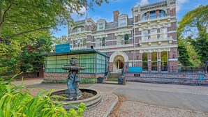 Un bâtiment historique doté d’une fontaine, d’une enseigne indiquant qu’il s’agit de l’hôtel Liverpool Aigburth, et d’un chemin piétonnier pavé.