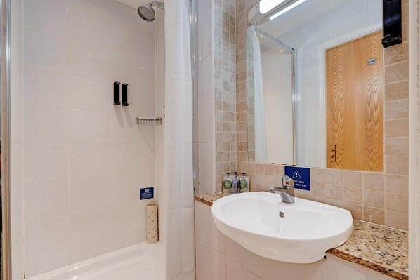 A bathroom with a shower, a sink, and a mirror.