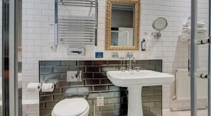Een badkamer met een wit toilet, een wastafel, een spiegel en een handdoekhouder.