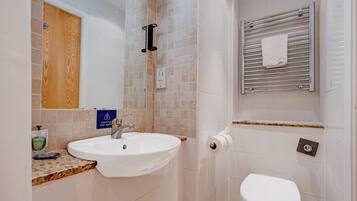 A bathroom with a sink, toilet, and a towel rack.