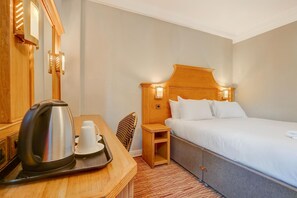 Une chambre d’hôtel comprenant un lit, une table de chevet, une bouilloire, une tasse et un plateau.