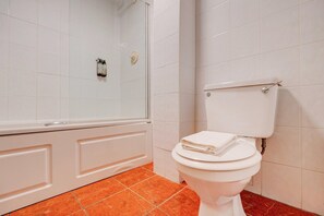 Et badeværelse med et hvidt toilet, et bruseområde og et flisegulv.