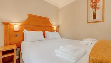 A hotel room with a large bed, two bedside tables, a nightstand, and a framed picture on the wall.