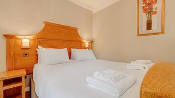 A hotel room with a large bed, two bedside tables, a nightstand, and a framed artwork on the wall.
