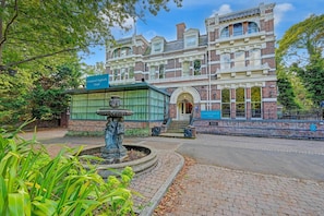 En historisk bygning med en fontæne, et skilt der viser, at det er Liverpool Aigburth Hotel, og en belagt sti.