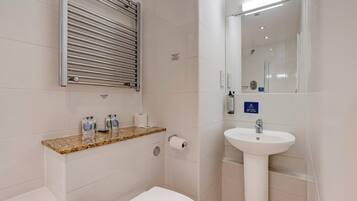 A bathroom with a toilet, sink, towel rack, and a mirror.