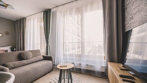 Ein modernes Wohnzimmer mit einer Couch, einem kleinen runden Tisch und einem Fernseher auf einem Holzboden.