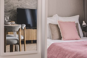 Une chambre comprenant un lit, une télévision, un coin repas avec des chaises et une table.