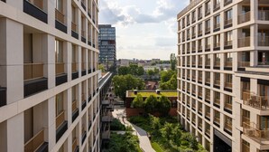 Ein Hochhaus mit mehreren Balkonen, einem zentralen Innenhof und Blick auf eine Stadtlandschaft.