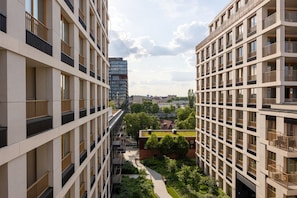 Un immeuble résidentiel de grande hauteur, doté de nombreux balcons, d’une cour intérieure et offrant une vue sur le paysage urbain.