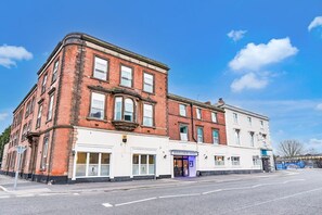 A corner building with a brick facade and a white section with a sign for 'Aston Court Hotel'. - Accessible Double Room (Derby)