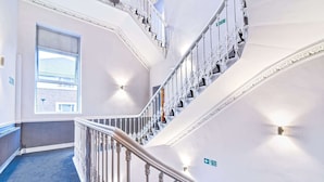 Un intérieur à plusieurs niveaux, doté d’un escalier, d’une grande fenêtre et d’une signalétique directionnelle.