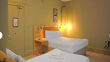 A hotel room with two beds, a wooden headboard, a small table, and a chair.