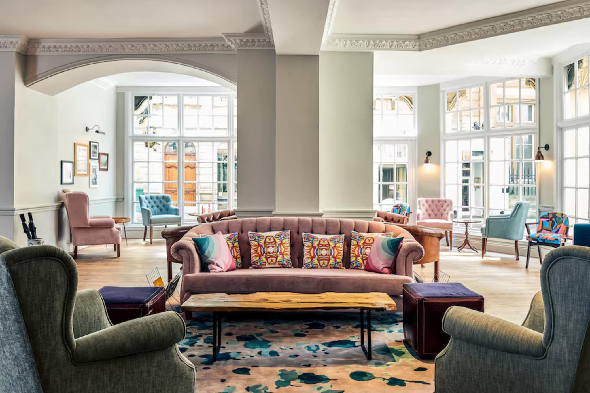 A spacious lounge with a large sofa, multiple armchairs, and a patterned rug.