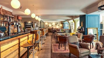A bar area with stools, a counter, and a variety of bottles. There are multiple seating areas with chairs and a sofa.