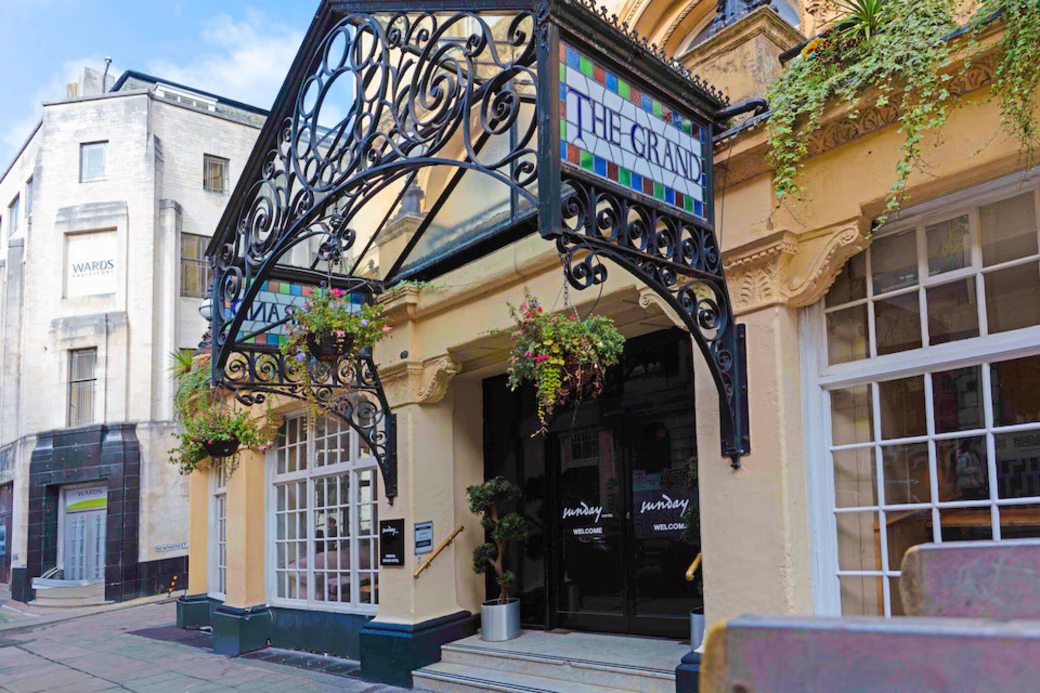 A building with a sign reading 'THE GRAND' and a wrought iron structure above the entrance.