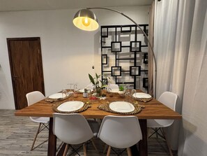 Ein Esstisch, gedeckt mit Tellern, Gläsern und einer Blumenvase.