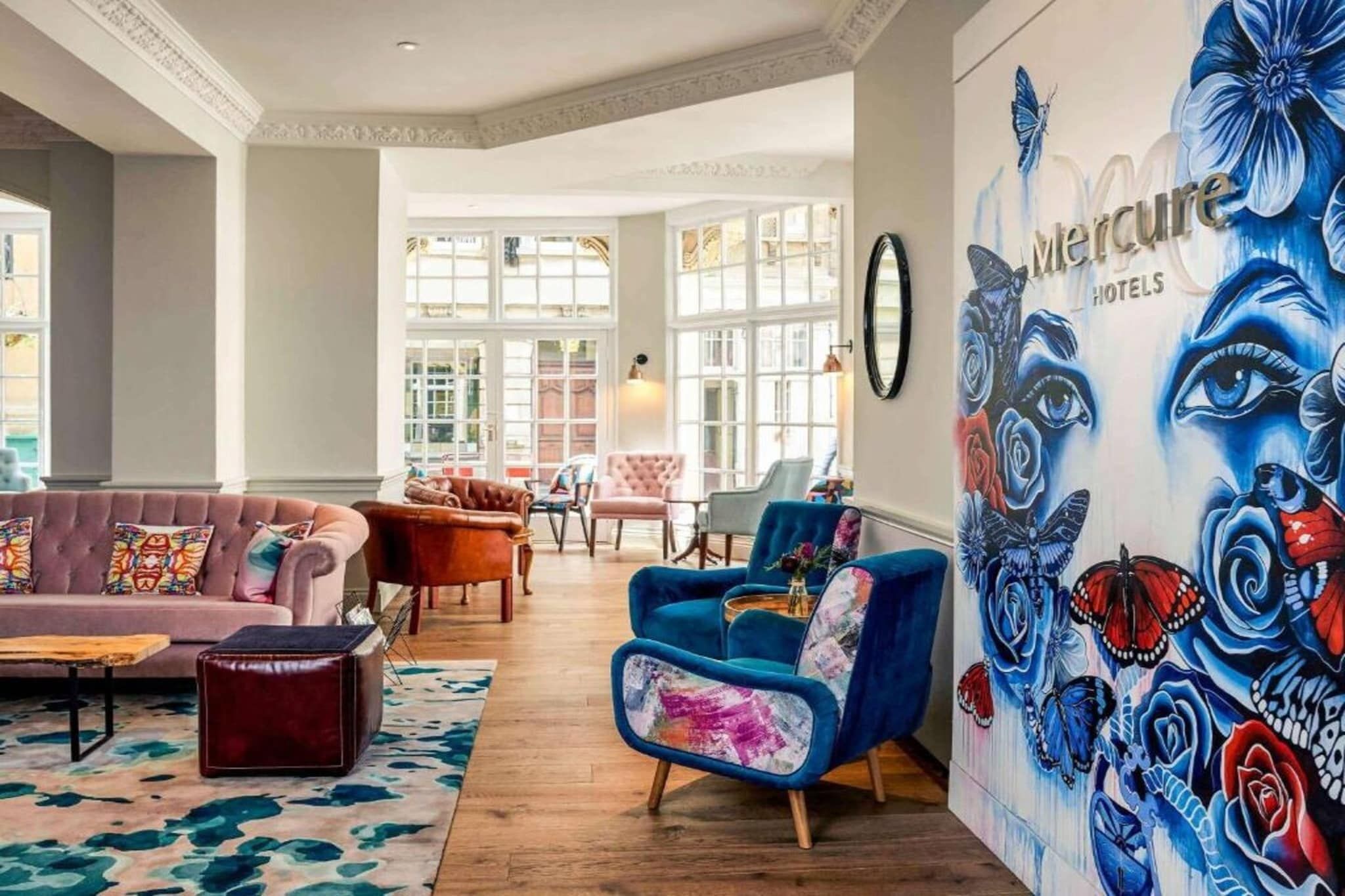 A spacious lobby with a large window, a blue armchair, and a colorful sofa.